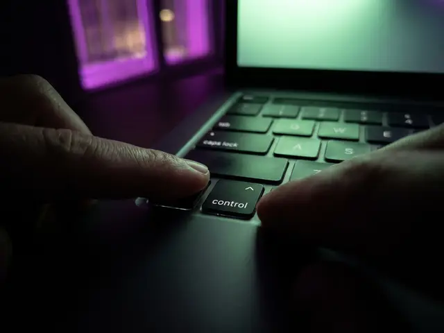 A finger holding the control key on a MacBook keyboard in a dark room